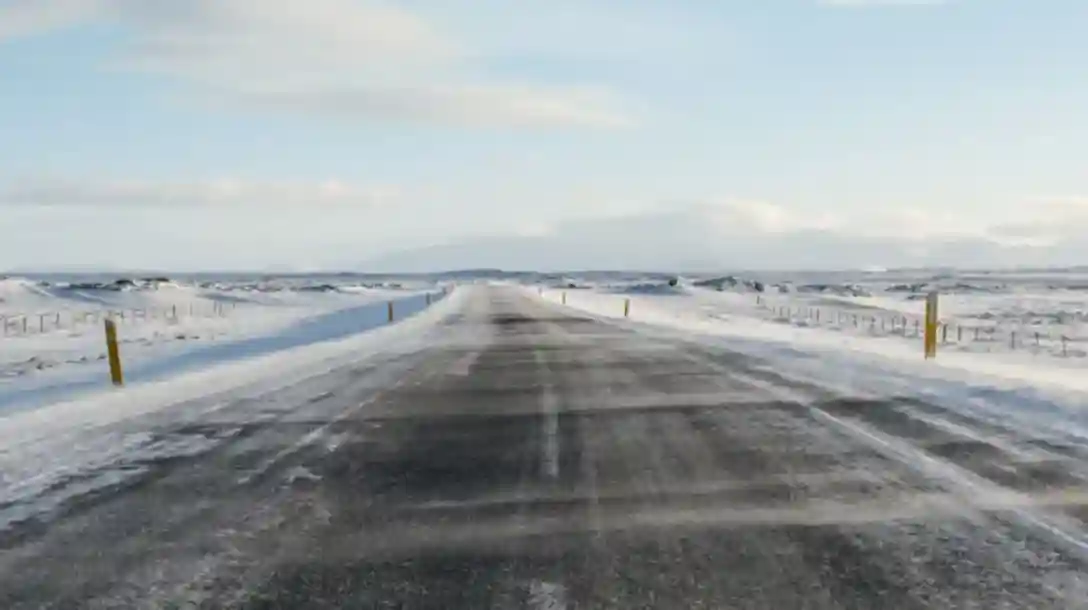 Asphalt road with sow capped landscape in the background.